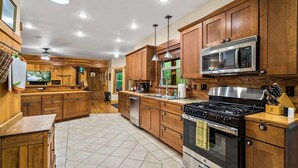 A kitchen with wooden cabinets, a microwave, stove, and a sink. - Summer Lodge Life! 5bd+4bath+HotTub+Sauna+EV (Ashford)