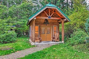 A wooden cabin with a green roof, two doors, and two chairs outside. - Summer Lodge Life! 5bd+4bath+HotTub+Sauna+EV (Ashford)