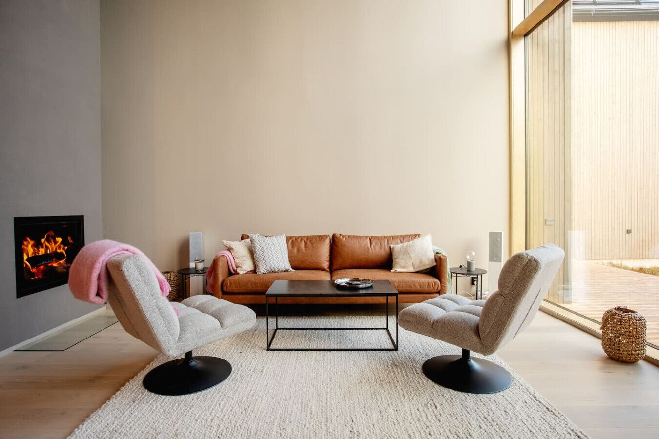 Un salon moderne avec un canapé en cuir marron, deux fauteuils gris, une table basse et une cheminée.