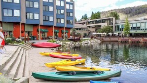 A row of kayaks lined up on a sandy beach next to a building with a red facade and a blue upper level. - Spacious 2-bedroom 2.5 Bath Townhome Walking Distance to World Class Skiing!  (Keystone)