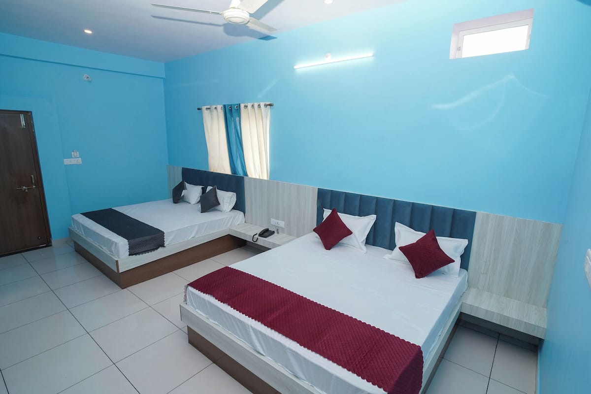 A hotel room with two beds, a ceiling fan, a window with curtains, and a small skylight.