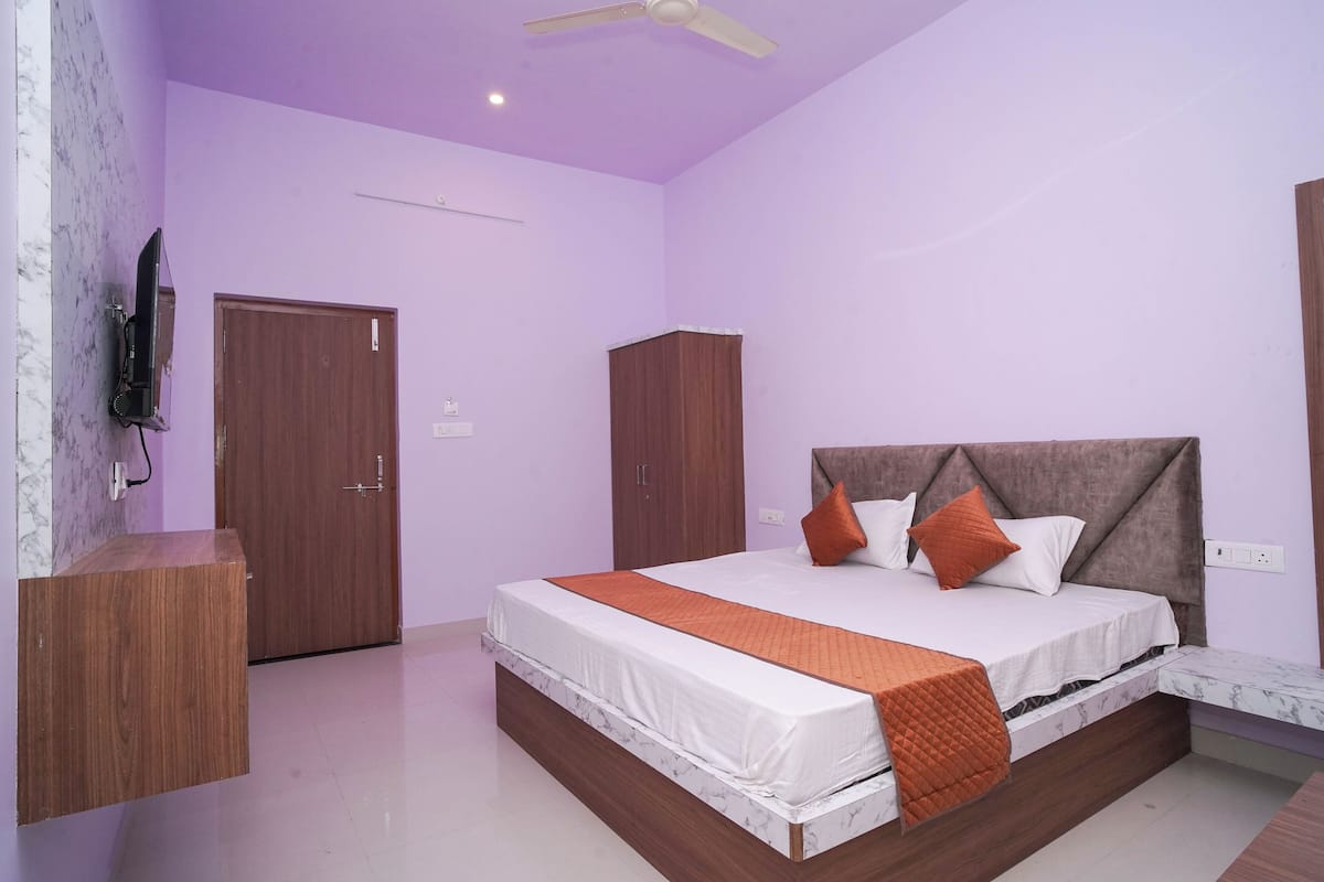 A bedroom with a bed, wooden wardrobe, and a television mounted on the wall.