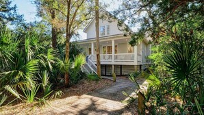 A two-story house with a covered porch and a wooden deck leading to the entrance.