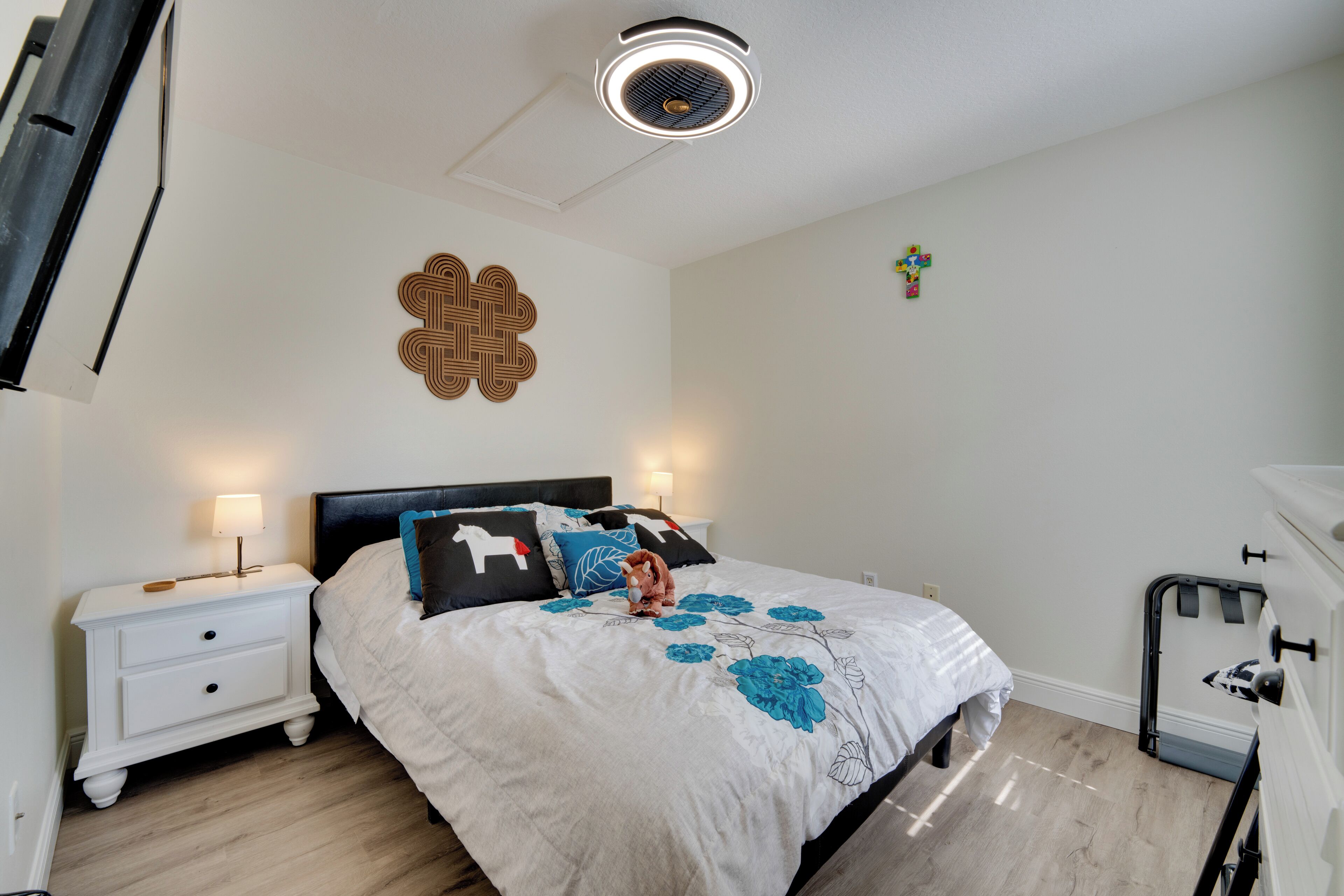 Une chambre à coucher comprenant un lit, une table de chevet, des éléments de décoration murale et un luminaire au plafond.