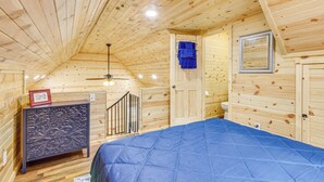 A wooden cabin room with a bed, a dresser, a door, and a ceiling fan. - Near Greenbrier River! Mtn-View Cabin w/ Fire Pit (Marlinton)