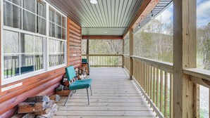 A wooden porch with a bench and a fire pit area. - Near Greenbrier River! Mtn-View Cabin w/ Fire Pit (Marlinton)