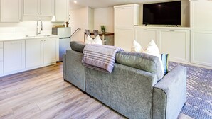 A modern living room with a grey sofa, white cabinets, a flat-screen TV, and a wooden floor. - 14 Miles to Sun Valley: Updated Getaway! (Hailey)