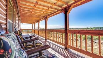 A covered porch with wooden railings and benches, overlooking a scenic landscape.
