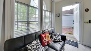 A living room with a black leather sofa, two patterned cushions, and a red cushion with "I Love You" text.