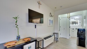 A modern kitchen with a flat-screen TV, a radiator, and a refrigerator.