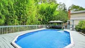 Una piscina al aire libre con cubierta de madera, rodeada de árboles verdes y frondosos.