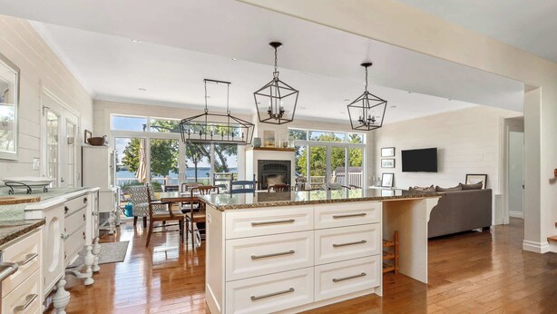 Una cocina amplia con una isla grande, piso de madera e iluminación colgante.