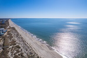 An aerial view of a beach with a clear sky, a sandy shoreline, and a few buildings along the coast. - Gorgeous 3 BR Oceanwalk Condo - Pool Onsite - Steps From Beach & Shops - Elevator (Oak Island)