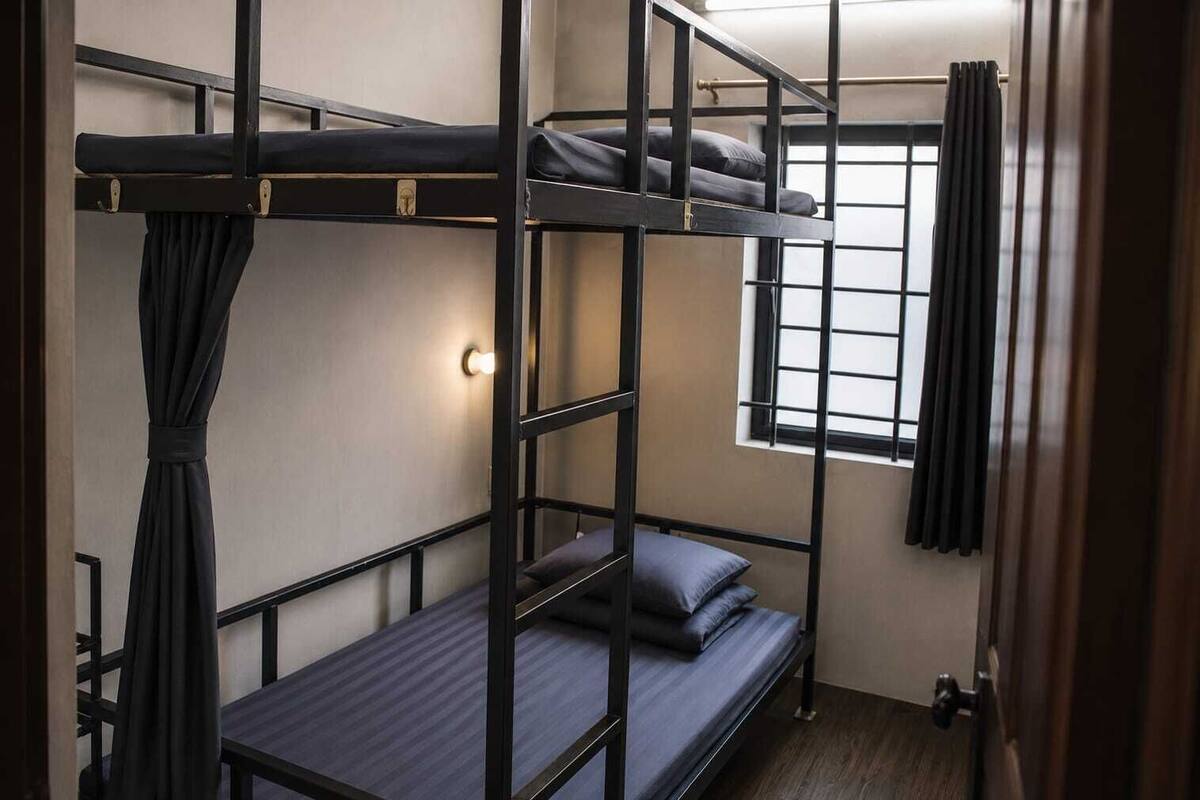 A bunk bed room with a window, curtains, and a light fixture.