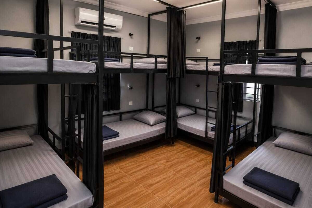 A bunk bed room with a wooden floor, a window, and an air conditioning unit.