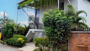 A modern building with a covered outdoor area, a staircase, and lush greenery. - The Drop Inn (Siem Reap)
