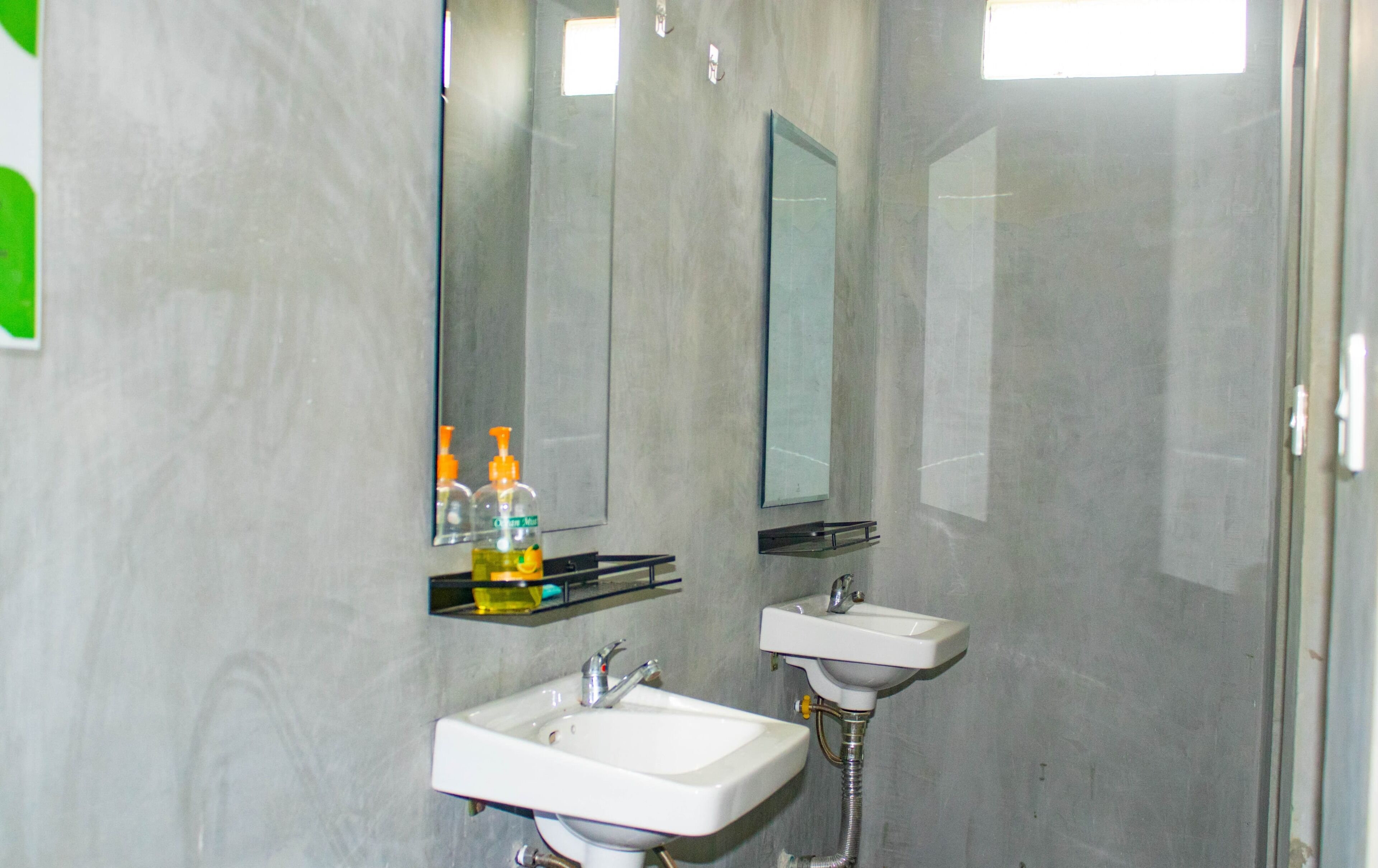 A bathroom with two sinks, a mirror, and toiletries on a shelf.