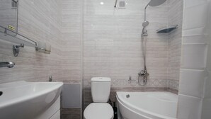 Et moderne badeværelse med et hvidt badekar, toilet og bruser.