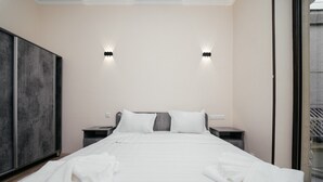 Et moderne hotelværelse med en stor seng, to sengeborde og et skab.