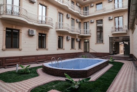 A courtyard with a swimming pool, a checkered floor, and a building with balconies.
