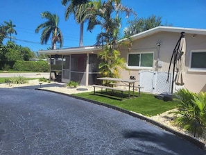 A single-story building with a covered patio, a small lawn, and a paved driveway.