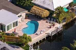 A swimming pool with lounge chairs and a thatched roof structure.
