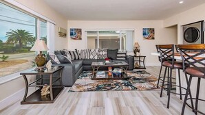A modern living room with a sectional sofa, a coffee table, and a dining area with bar stools. - Diana's Waterfront Villa (Fort Lauderdale)