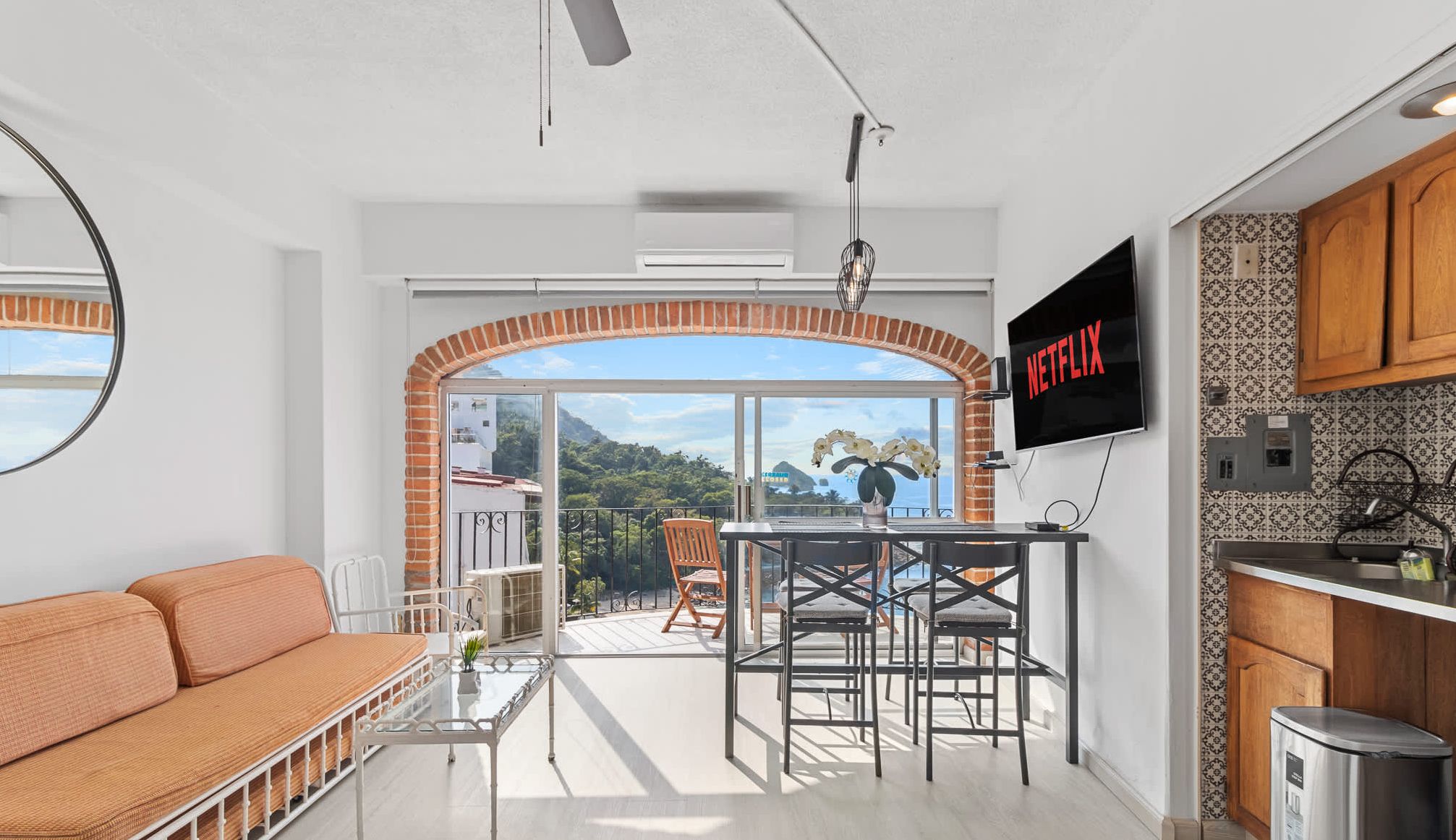 A modern living space with a balcony, a dining area, and a kitchen.