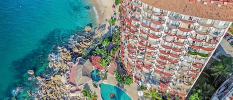 A high-rise hotel with multiple balconies, a pool area, and a beachside location.