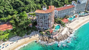 A resort with a beachfront, a circular building with balconies, and a pool area.
