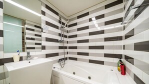 A bathroom with a large bathtub, a sink, and a shower. The walls have a black and white tile pattern. - Hotel INN Seoul (Seoul)