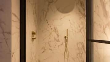Eine moderne Dusche mit Marmorwänden und einer Glasabtrennung.