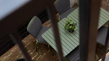A dining area with a table and chairs, a potted plant, and a brick wall.