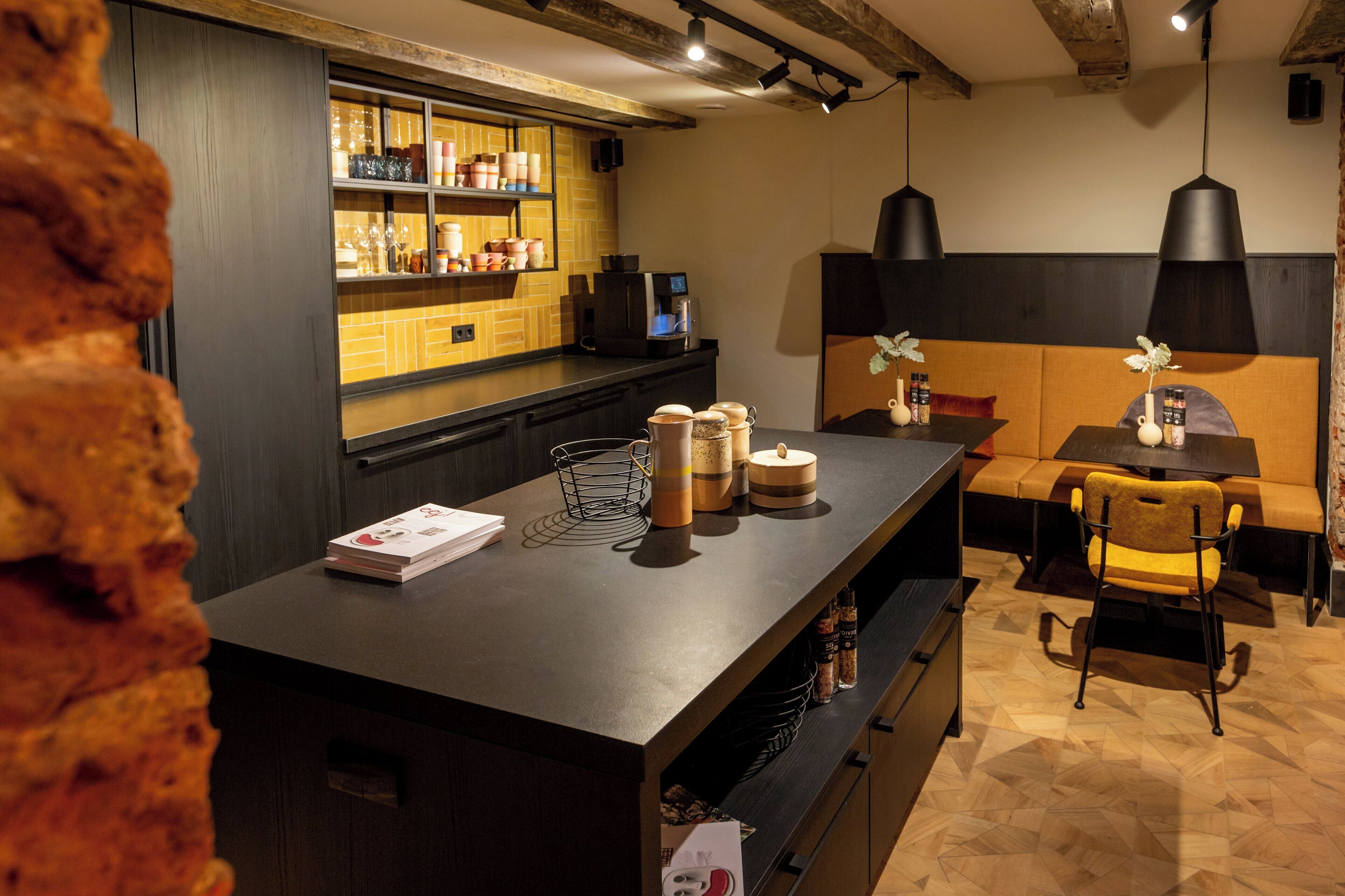Un área de bar moderna con una barra, estantes llenos de botellas, una máquina de café y una zona de estar con un sofá y sillas.
