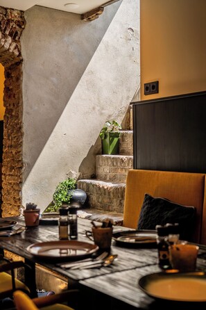 Cozy dining area with a wooden table, exposed brickwork, and a potted plant.