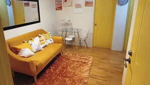 Un espace de vie compact comprenant un canapé, une table à manger et un miroir.