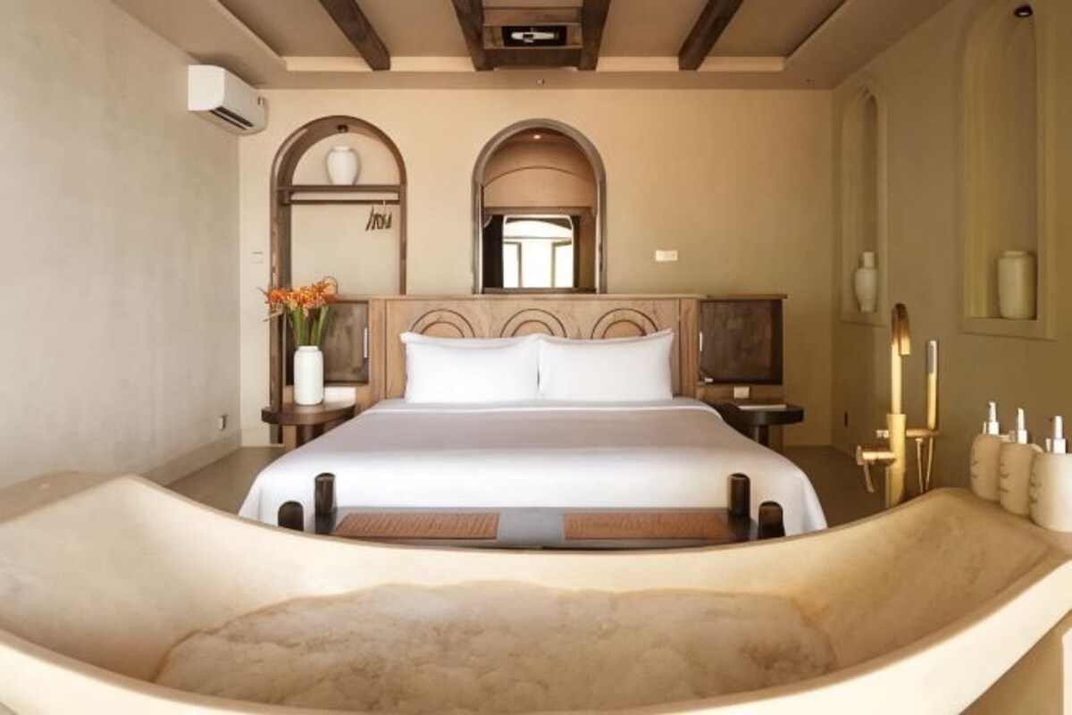 A bedroom with a large bed, a bathtub, and a TV.