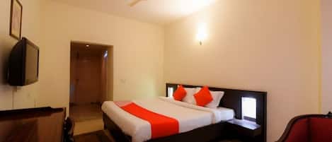 Ein Hotelzimmer mit Bett, Schreibtisch, Sessel, Deckenventilator und Fernseher.