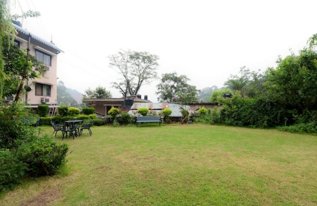 A grassy courtyard with a bench, a table, and a building in the background.