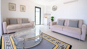 A modern living room with two sofas, a glass coffee table, and a kitchen in the background. - 125 Quinta do Paraiso, elegant Holiday Villa! (Carvoeiro)