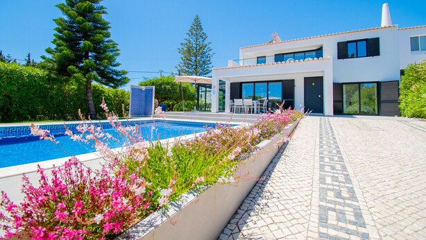 A modern house with a swimming pool, outdoor seating, and a garden with flowers. - 125 Quinta do Paraiso, elegant Holiday Villa! (Carvoeiro)