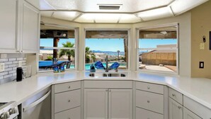 A modern kitchen with white cabinetry, a built-in stove, and a view of a pool and outdoor seating area. - Luxury Retreat Pool House with spectacular views!

 (Lake Havasu City)