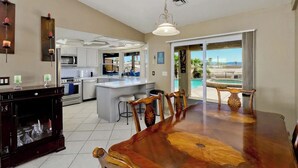 A spacious kitchen with white cabinets, a large island, and a dining area with a wooden table and chairs. - Luxury Retreat Pool House with spectacular views!

 (Lake Havasu City)
