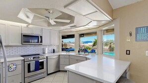 A modern kitchen with a large island, white cabinetry, and a view of a pool and outdoor seating. - Luxury Retreat Pool House with spectacular views!

 (Lake Havasu City)