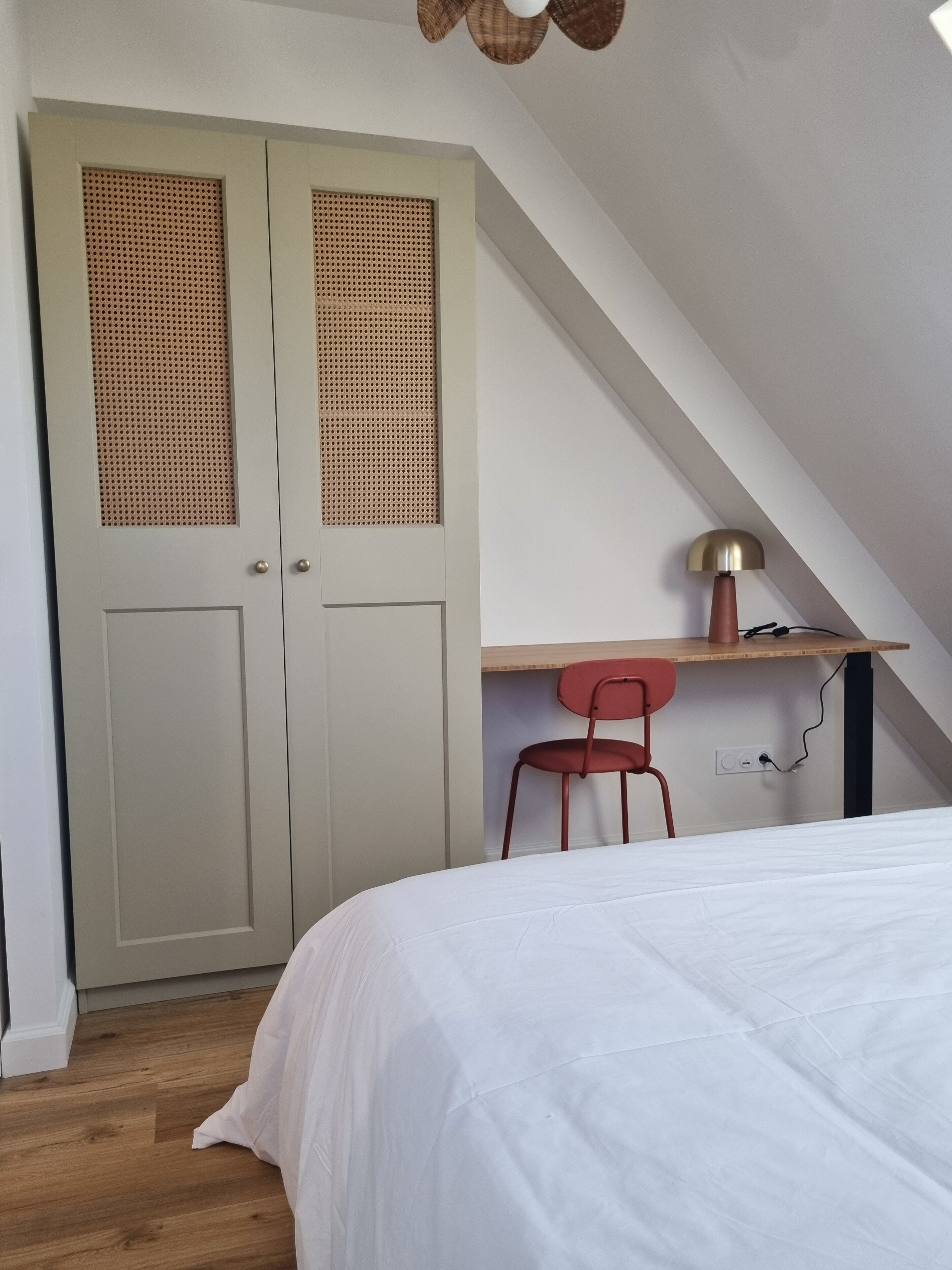 A bedroom with a bed, a desk, a chair, and a wardrobe.