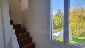 A staircase leading to a second floor with a large window providing a view of a garden.