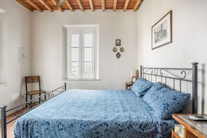 Ein Schlafzimmer mit Bett, Fenster, Stuhl, Nachttisch und Wanddekorationen.