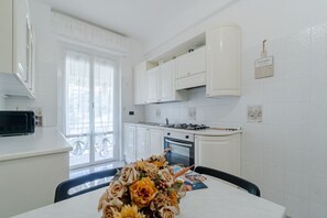 A modern kitchen with white cabinets, a gas stove, and a dining table with a floral centerpiece.