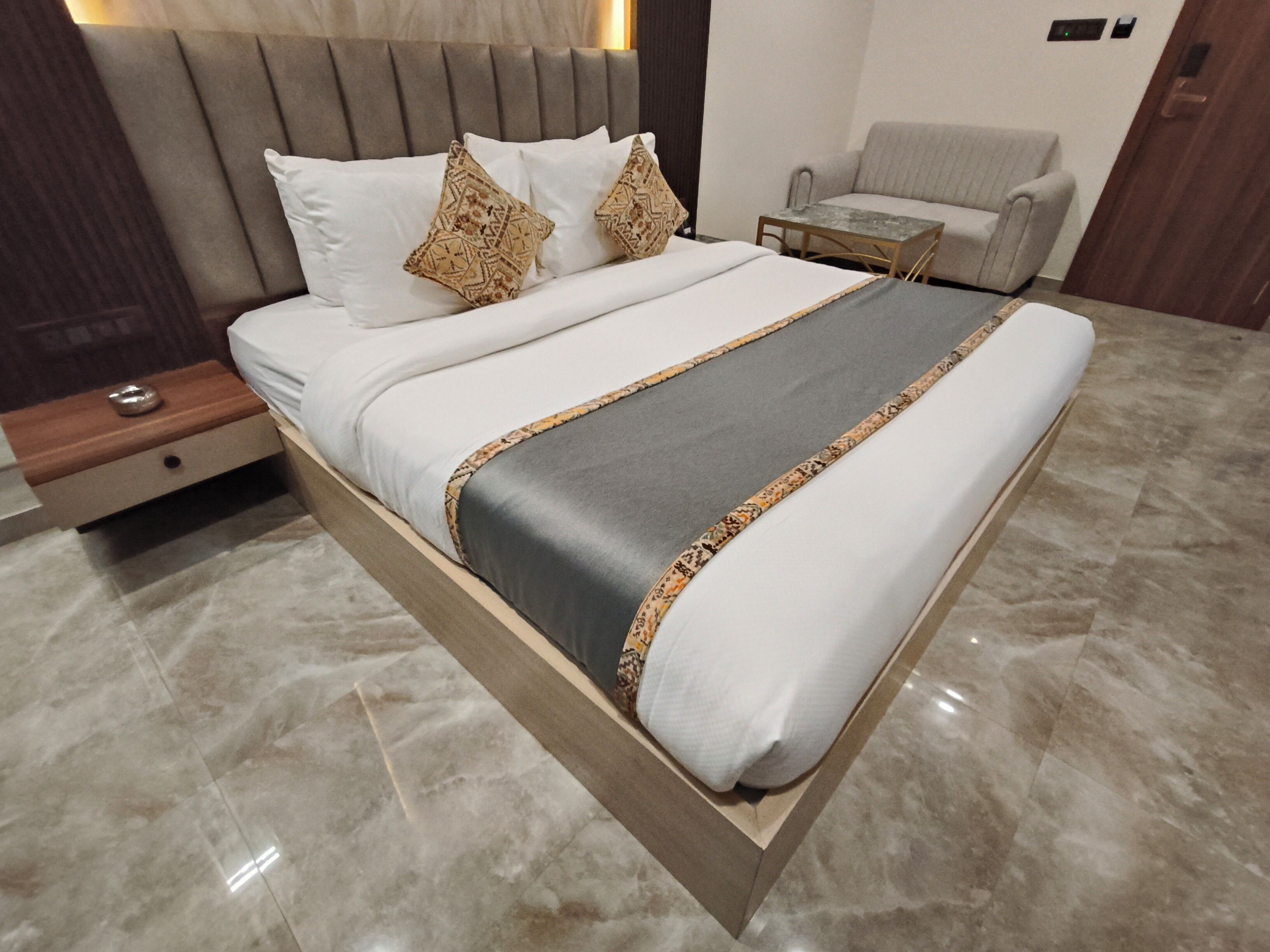 A modern bedroom with a bed, a nightstand, a small table, and a chair.