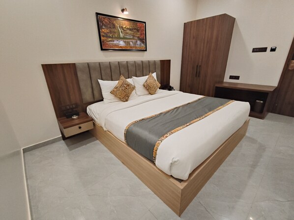 A modern bedroom with a large bed, a nightstand, a wardrobe, and a painting on the wall. - Light House Suites Hubballi (Hubli)